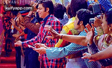 a group of people are standing in a line with their hands up .