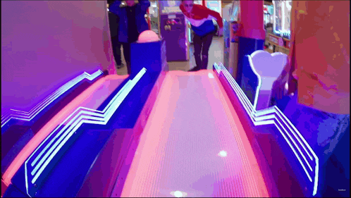 a man is bowling on a bowling alley that is lit up