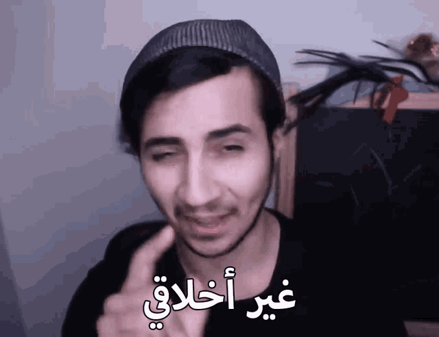 a man wearing a hat is making a funny face and has arabic writing on his face