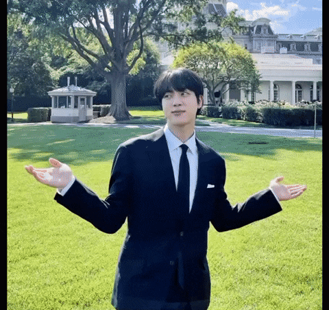 a man in a suit and tie is standing in front of the white house .