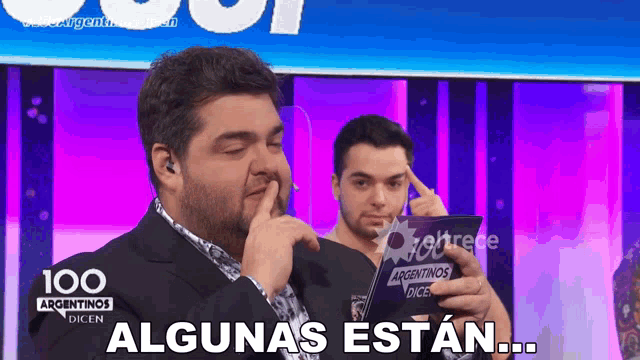a man holds his finger to his mouth while holding a card that says 100 argentinas dicen