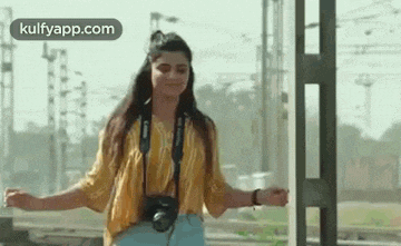 a woman is standing on a train platform with her arms outstretched .