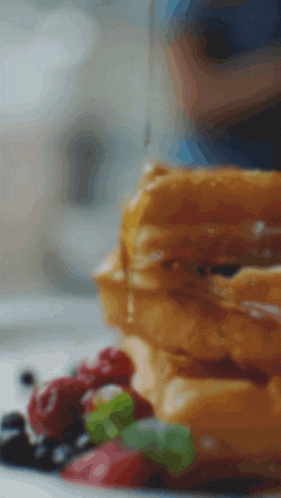 a stack of waffles with syrup and berries on a table