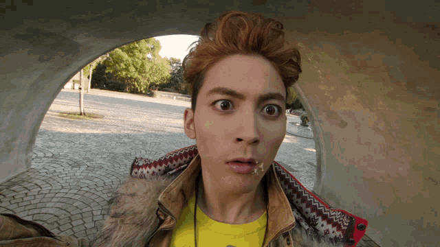 a young man with red hair and a yellow shirt is making a funny face