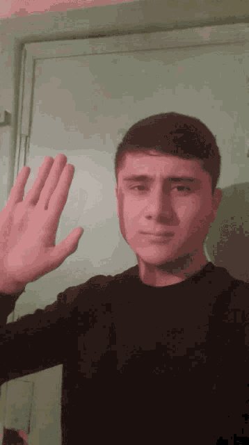 a young man in a black shirt waves his hand