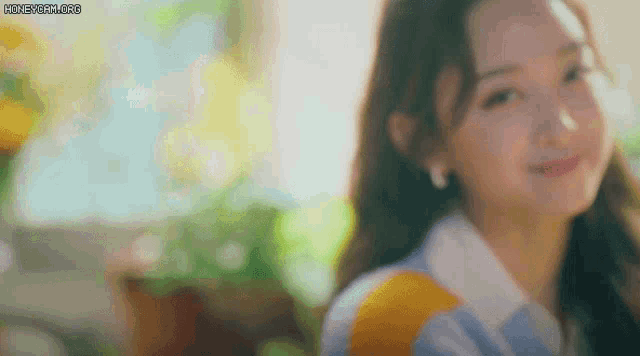 a close up of a woman 's face with a blurry background and the sun shining on her face .