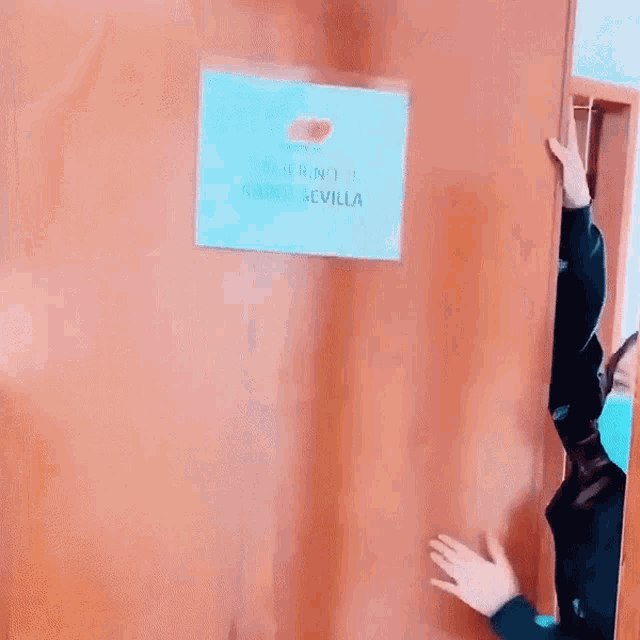 a woman wearing a mask is standing in front of a door that has a sign on it that says camerina kahol sevilla