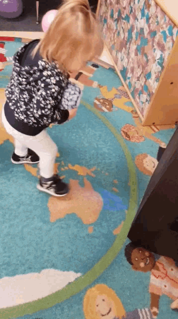 a little girl is standing on a rug with a map on it