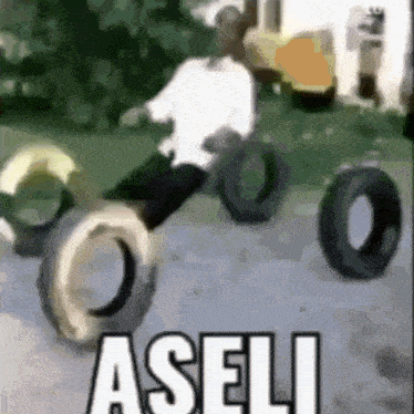 a man is sitting on a pile of tires with the word aseli written on it .