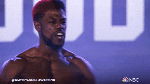 a shirtless man stands in front of a nbc sign