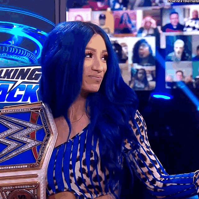 a woman with blue hair is wearing a king tck championship belt