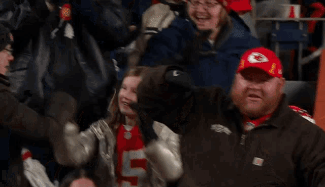a man wearing a chiefs hat stands in a crowd