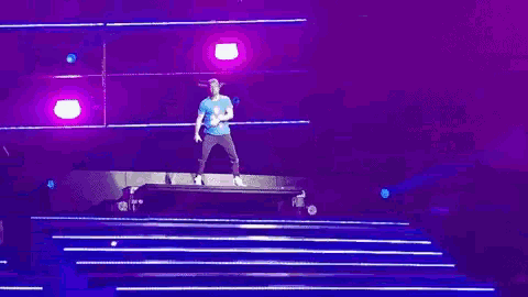 a person is dancing on a stage with purple lights behind them