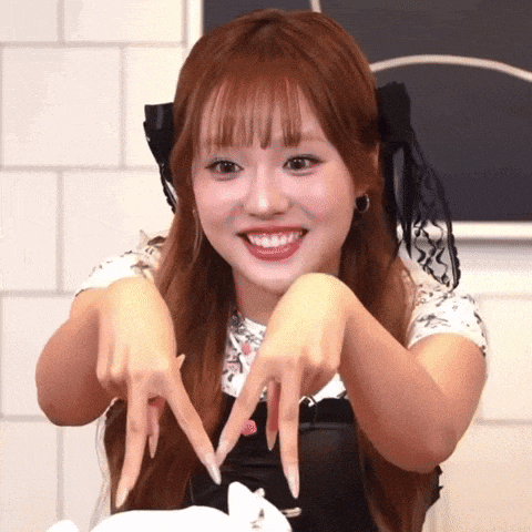 a girl with long nails is making a heart shape with her hands