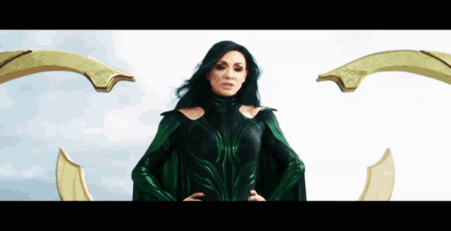 a woman in a green and black costume is standing in front of a white sky