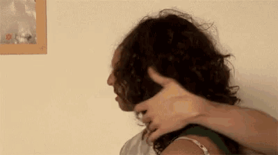 a woman with curly hair is being held by a man in front of a picture on the wall