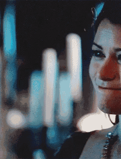 a close up of a woman 's face with a blurry background of candles