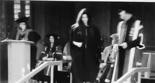 a black and white photo of a woman in a graduation gown