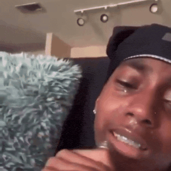 a woman is crying and smiling while sitting on a couch in a living room .