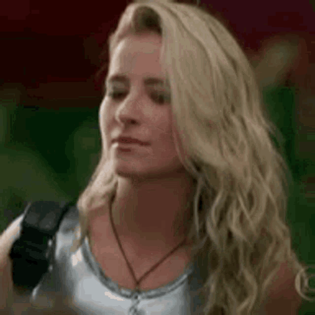 the woman is wearing a silver tank top and a black necklace .