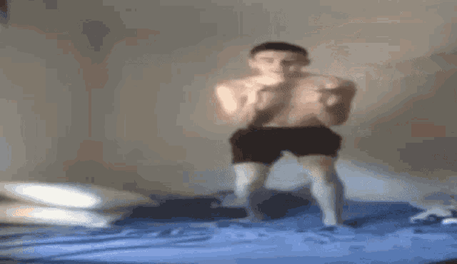 a shirtless man is standing on top of a bed .