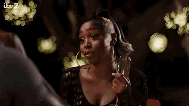 a woman holds a glass of champagne in front of a sign that says itv2