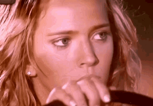 a close up of a woman 's face with her hand on her face