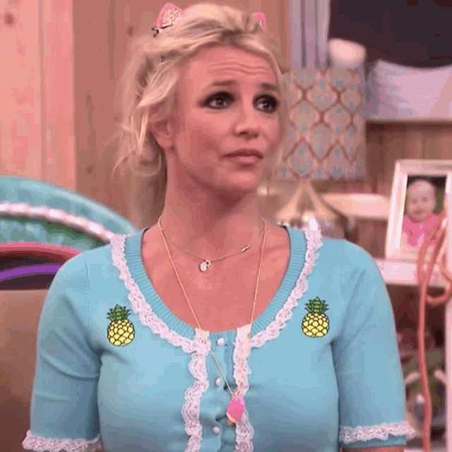 a woman wearing a blue cardigan with pineapples on it