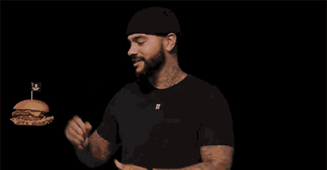 a man with a tattoo on his arm eating a hamburger