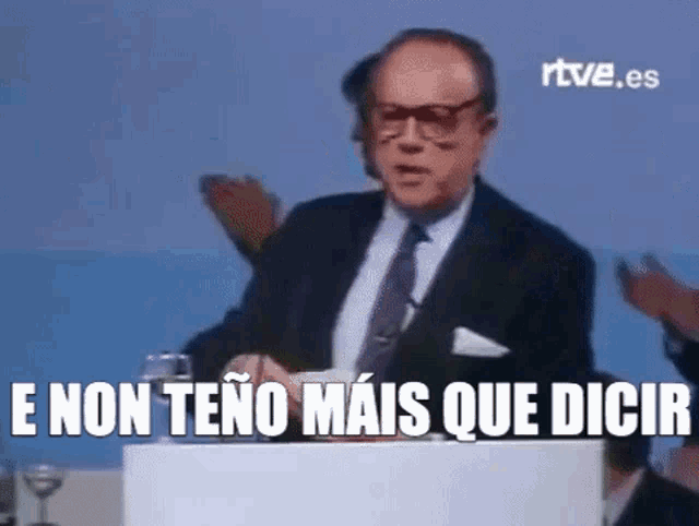 a man in a suit and tie is standing at a podium giving a speech in spanish .