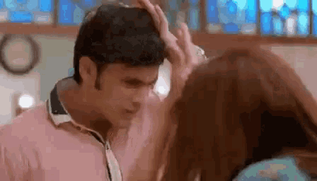 a man is touching a woman 's head while they are kissing .