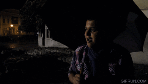 a man holding an umbrella in the dark with gifrun.com in the lower right corner