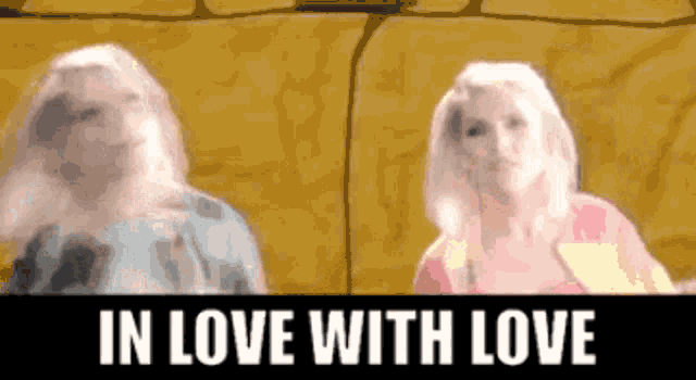 two blonde women are standing next to each other with the words in love with love above them .