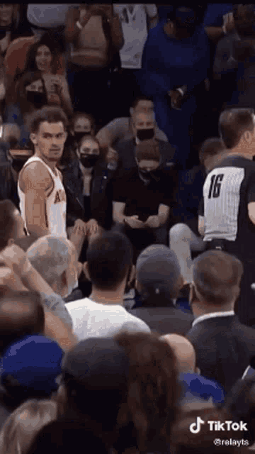 a basketball player is standing in front of a crowd of people wearing masks .