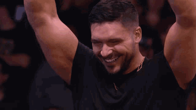 a man in a black shirt is smiling with his arms in the air .