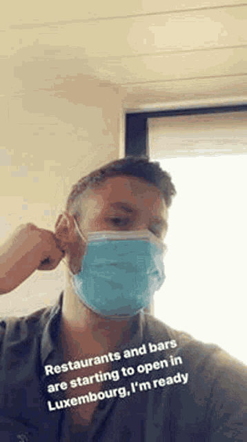 a man wearing a face mask is covering his ears .