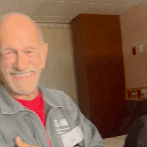 a man wearing a grey jacket with the letter h on it smiles