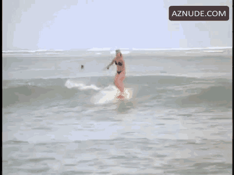 a woman in a bikini is riding a wave on a longboard in the ocean .