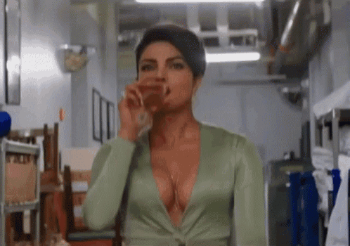 a woman in a very plunging neckline is drinking from a glass .