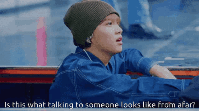 a man wearing a beanie and ear buds is talking to someone