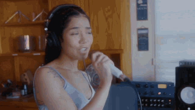 a woman in headphones is singing into a microphone .