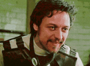 a man with curly hair and a beard is smiling while wearing a leather vest .