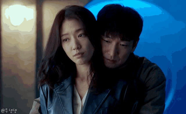 a man and a woman are hugging each other with a blue background behind them