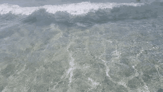 a wave is breaking on a rocky shoreline in the ocean