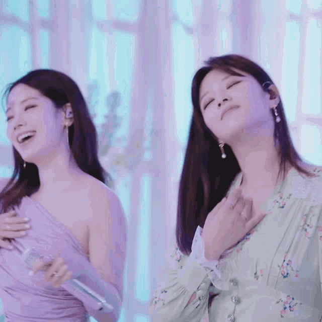 two women are standing next to each other with their eyes closed and their hands on their chests