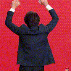 a man in a suit is standing in front of a red wall