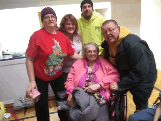 a group of people posing for a picture with one wearing a christmas tree sweater