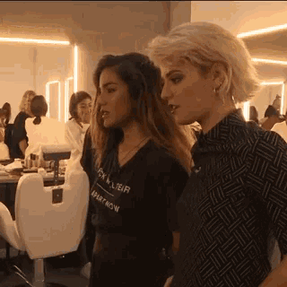 two women are standing next to each other and one of them is wearing a shirt that says " sk & ueir "