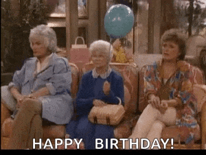 three older women are sitting on a couch with a blue balloon and a birthday card .