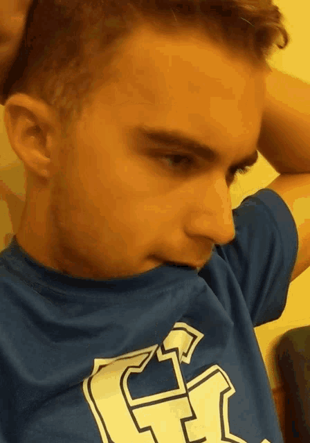 a man wearing a blue t-shirt with a white g on it